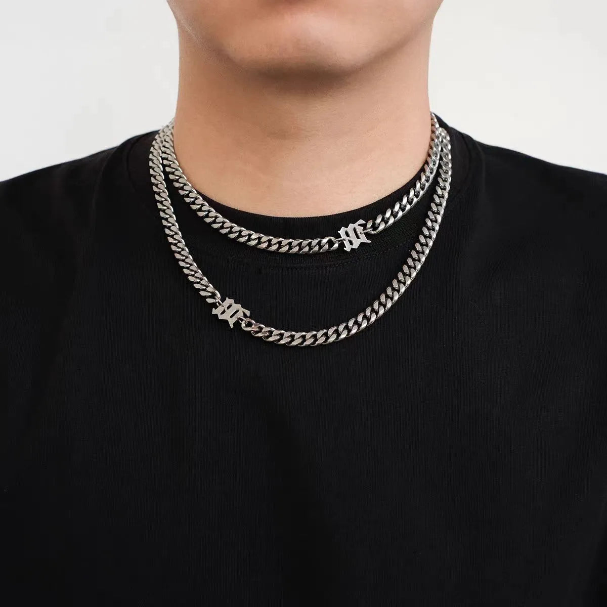 Model wearing a stainless steel Cuban link necklace featuring a gothic letter charm with streetwear styling.