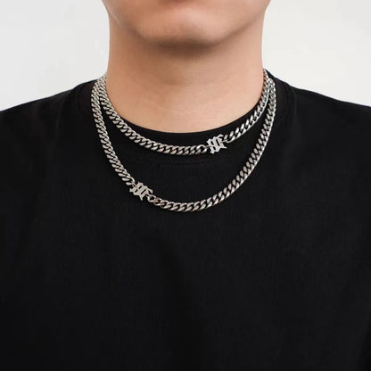 Model wearing a stainless steel Cuban link necklace featuring a gothic letter charm with streetwear styling.