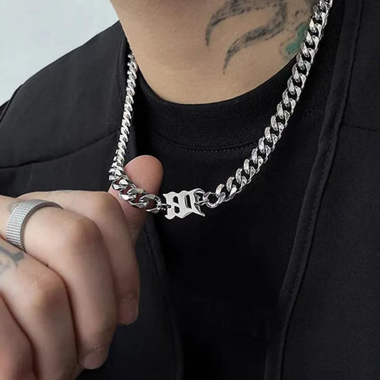 Model wearing a stainless steel Cuban link necklace featuring a gothic letter charm with streetwear styling.