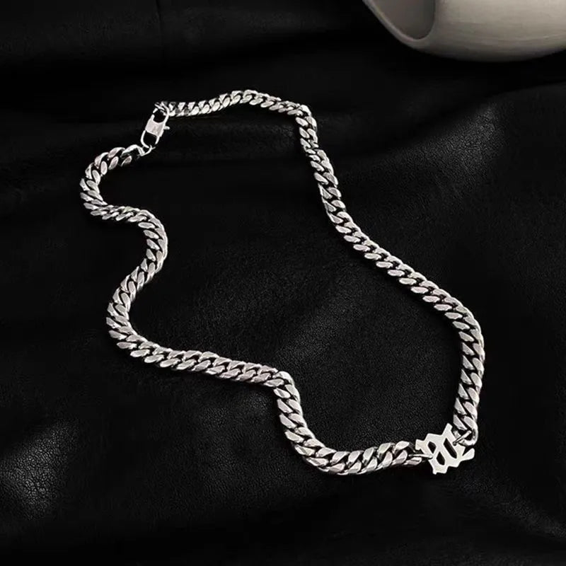 Silver stainless steel Cuban link necklace with gothic letter center charm on a white background.