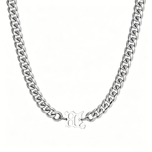 Silver stainless steel Cuban link necklace with gothic letter center charm on a white background.