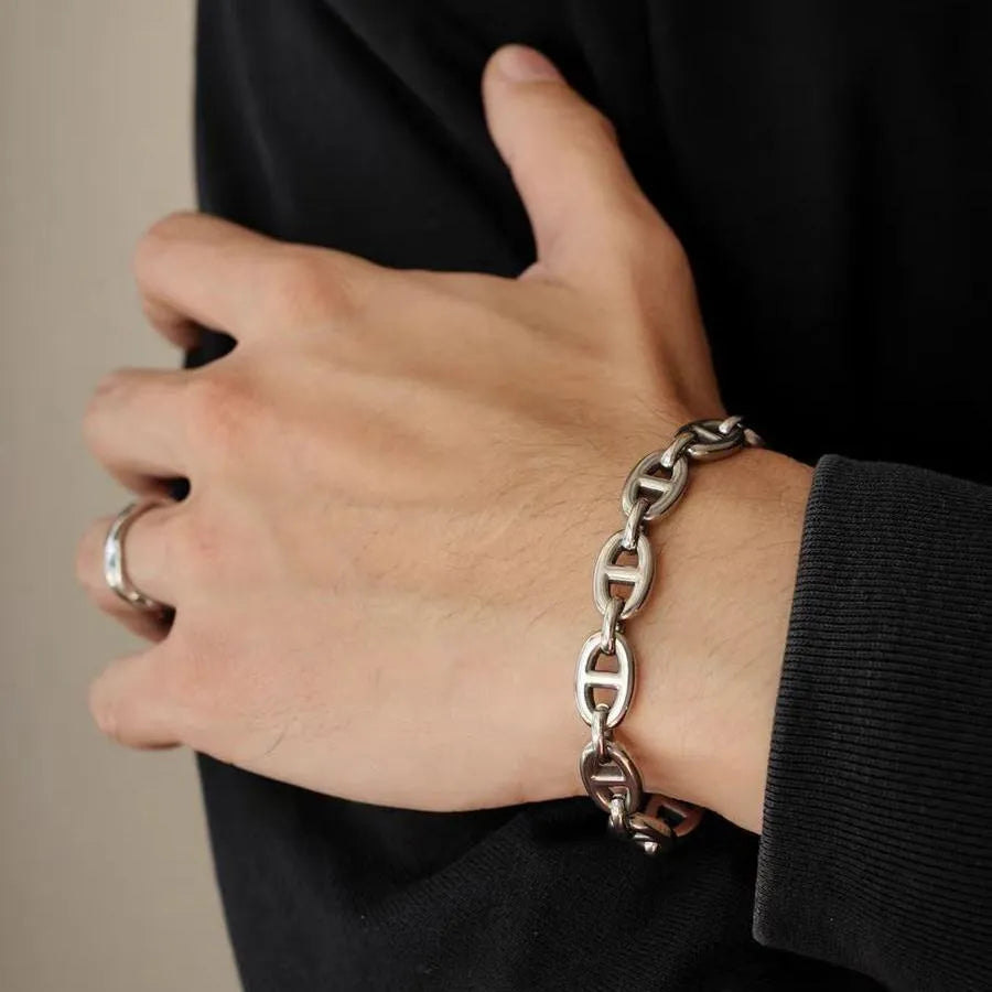Model wearing a polished stainless steel oval link bracelet with a minimalist streetwear style.